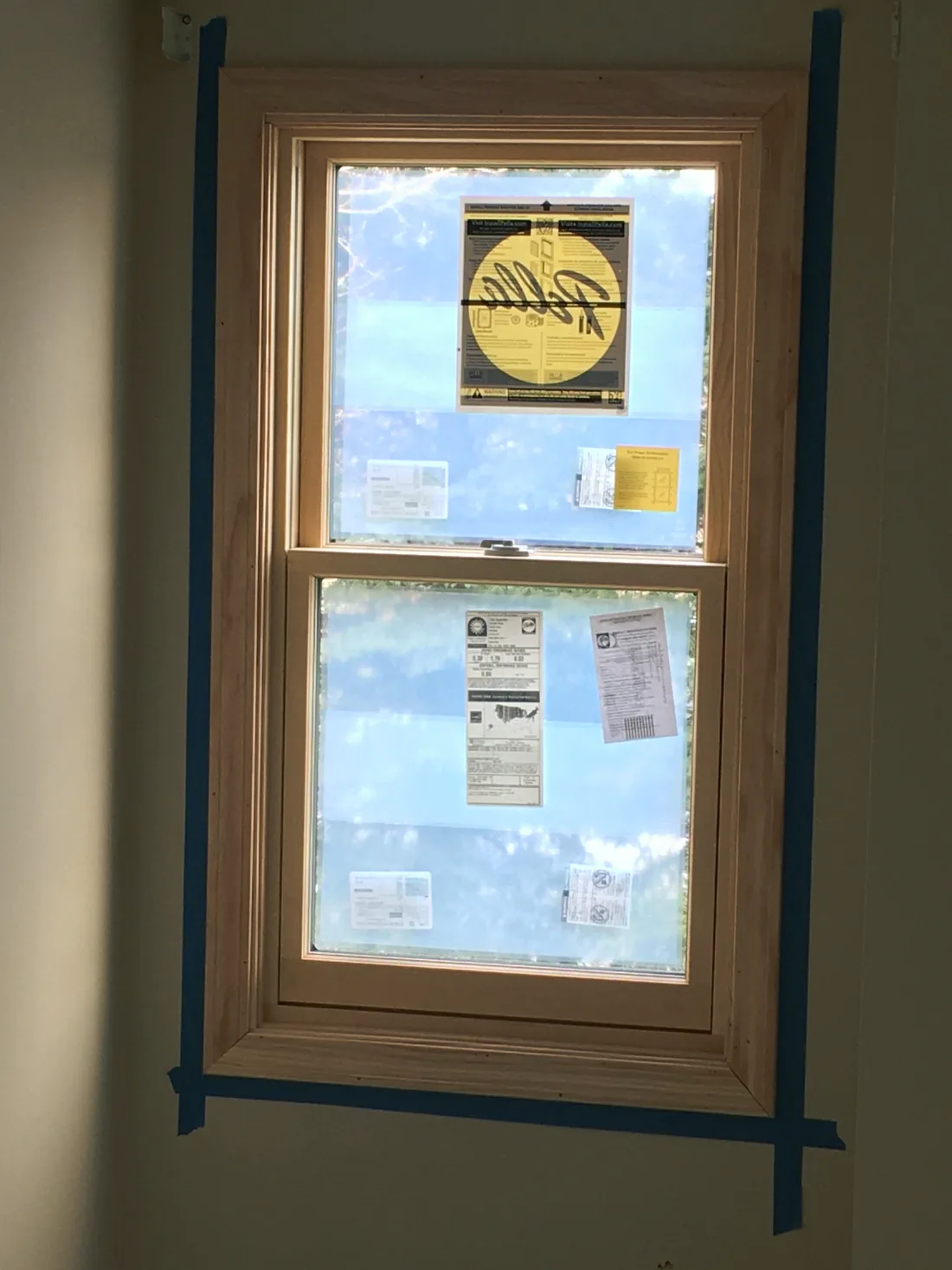 A window with new trim, taped off along every edge before painting.
