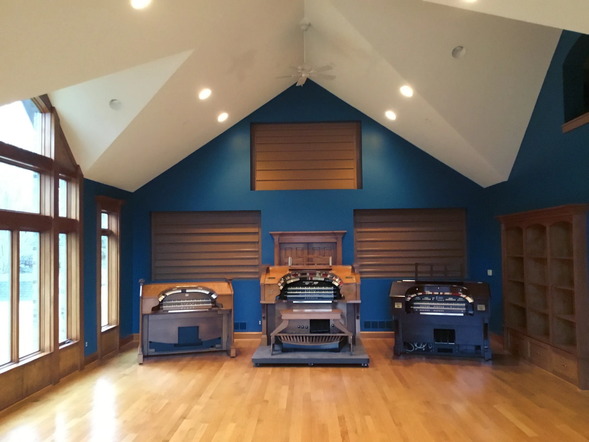 A music studio with a vaulted ceiling and an 18-foot deep blue wall, three organs on the oak floor.